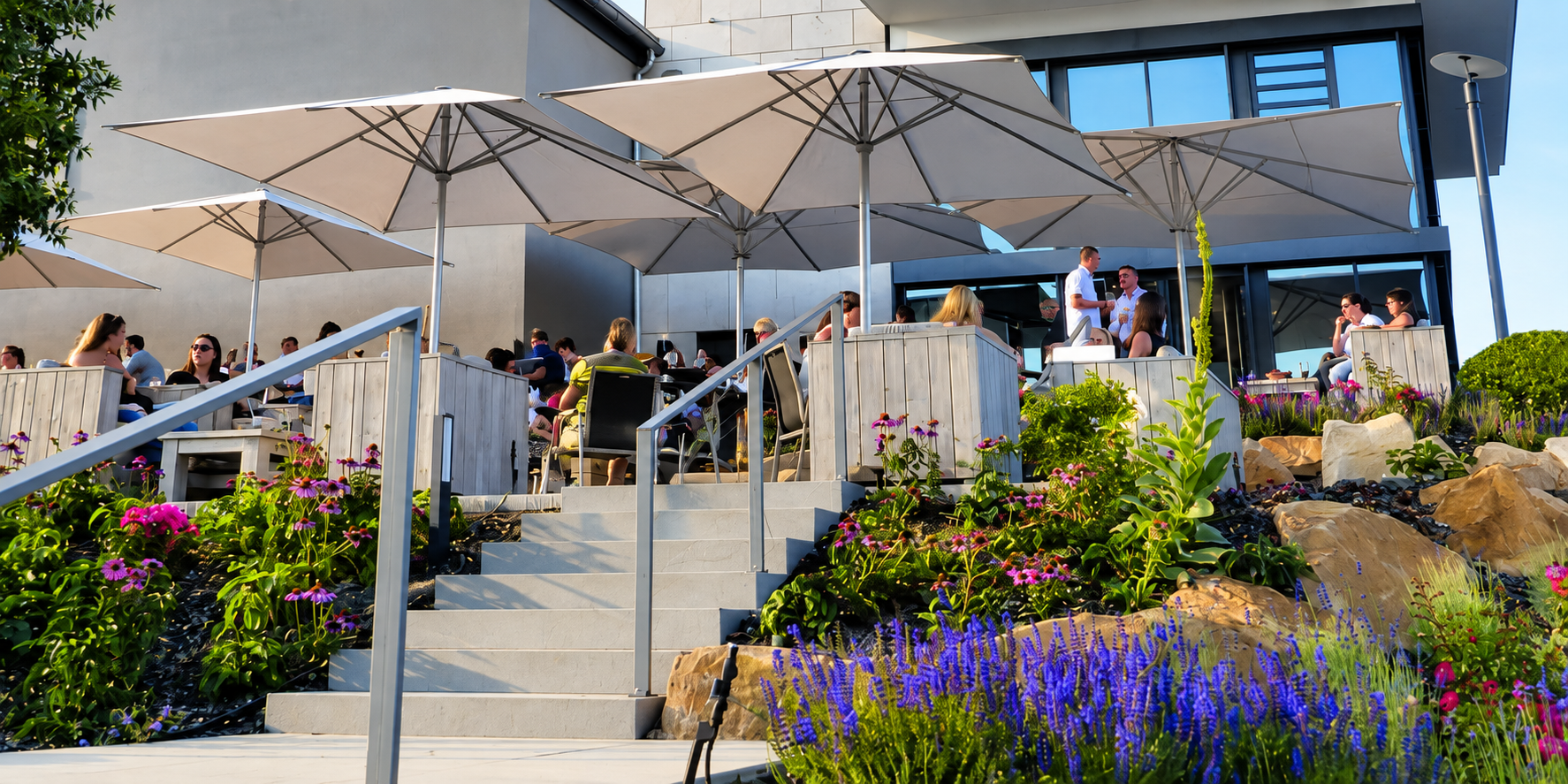Large market umbrellas shading a busy restaurant patio terrace